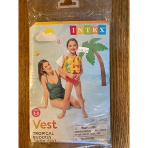 May include: A packaged Intex Tropical Buddies swim vest for ages 3-5. The packaging shows a child wearing the yellow and red vest with a tropical design. The packaging also includes the Intex logo and a warning about small parts.