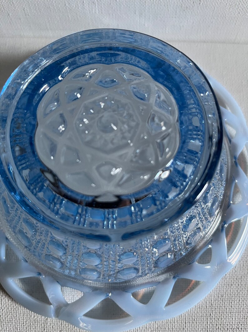 K&ouml;nnte beinhalten: Eine blaue Glassch&uuml;ssel mit einer wei&szlig;en Spitzenborte. Die Sch&uuml;ssel hat ein strukturiertes Design und ist aus undurchsichtigem Glas.