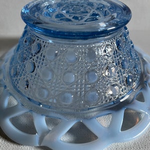 K&ouml;nnte beinhalten: Eine hellblaue Glassch&uuml;ssel mit einem gewellten Rand und einem strukturierten Boden. Die Sch&uuml;ssel ist aus Milchglas und hat einen Vintage-Look.