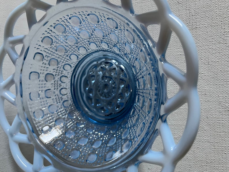 K&ouml;nnte beinhalten: Eine blaue Glassch&uuml;ssel mit einem wei&szlig;en Spitzenmuster am Rand. Die Sch&uuml;ssel hat ein strukturiertes Muster auf dem Boden.