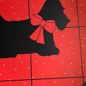 May include: A red and black decorative tray featuring a black silhouette of a dog with a red bow. The tray has a red background with white polka dots and black grid lines.