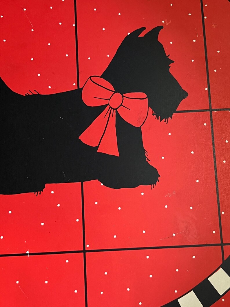 May include: A red and black decorative tray featuring a black silhouette of a dog with a red bow. The tray has a red background with white polka dots and black grid lines.