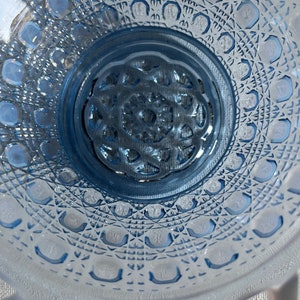 K&ouml;nnte beinhalten: Eine blaue Glassch&uuml;ssel mit einem dekorativen, rautenf&ouml;rmigen Muster. Die Sch&uuml;ssel hat einen gewellten Rand und eine erhabene Mitte.