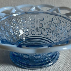 K&ouml;nnte beinhalten: Eine blaue Glassch&uuml;ssel mit einem wei&szlig;en Spitzenrand. Die Sch&uuml;ssel hat ein strukturiertes Muster aus kleinen Kreisen und steht auf einem wei&szlig;en Hintergrund.