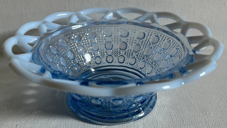 K&ouml;nnte beinhalten: Eine blaue Glassch&uuml;ssel mit einem wei&szlig;en Spitzenrand. Die Sch&uuml;ssel hat ein strukturiertes Muster aus kleinen Kreisen und steht auf einem wei&szlig;en Hintergrund.