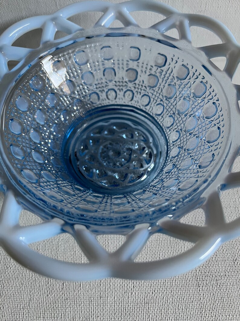 K&ouml;nnte beinhalten: Eine blaue Glassch&uuml;ssel mit einem wei&szlig;en Spitzenmuster am Rand. Die Sch&uuml;ssel hat eine strukturierte, gemusterte Oberfl&auml;che.