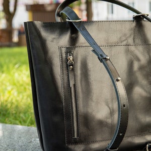 Puede incluir: Bolso tote de cuero negro con un bolsillo con cremallera y correas ajustables. El bolso tiene un dise&ntilde;o elegante y moderno.