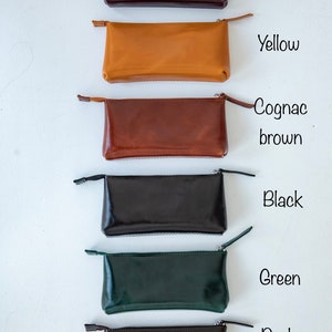 May include: Six leather zippered pouches in different colors: burgundy, yellow, cognac brown, black, green, and dark brown.