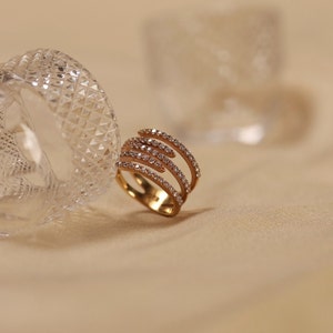 Puede incluir: Un anillo de oro con múltiples bandas engastadas con pequeños diamantes transparentes.