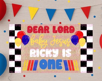Può includere: Striscione con la scritta "DEAR LORD baby Jesus RICKY IS ONE" in rosso, giallo e blu. Lo striscione ha un tema di corse con bandiere a scacchi e palloncini. Sono presenti anche palloncini rossi, blu e gialli.