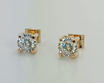 May include: A pair of gold stud earrings with a clear round gemstone in the center.