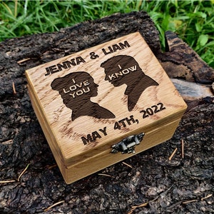 May include: A wooden box with a hinged lid, engraved with the text "Jenna & Liam", "I Love You", "I Know", "May 4th, 2022", and silhouettes of a man and woman.