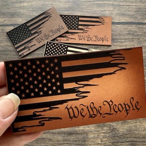 May include: Three leather patches with a distressed American flag design and the text "We the People".