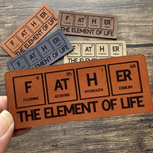 May include: A brown leather plaque with the word "FATHER" spelled out using the chemical symbols for the elements fluorine, astatine, hydrogen, and erbium. The plaque also includes the text "THE ELEMENT OF LIFE".