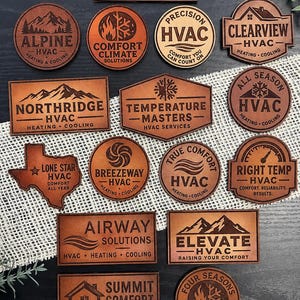 May include: A collection of brown leather patches featuring various HVAC company logos and names, including Summit HVAC, Alpine HVAC, Comfort Climate Solutions, Precision HVAC, Clearview HVAC, Northridge HVAC, Temperature Masters, All Season HVAC, Lone Star HVAC, Breezeway HVAC, True Comfort HVAC, Right Temp HVAC, Airway Solutions, Elevate HVAC, Summit Comfort HVAC, and Four Seasons HVAC.