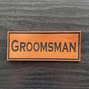 May include: A brown leather patch with the word "GROOMSMAN" embossed in black lettering.