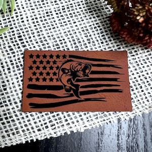 May include: A brown leather patch with a distressed American flag design and a black silhouette of a bass fish jumping out of the water.