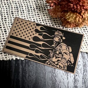 May include: A brown paper sticker with a black and white illustration of a firefighter in front of an American flag with flames. The firefighter is wearing a helmet and a gas mask.