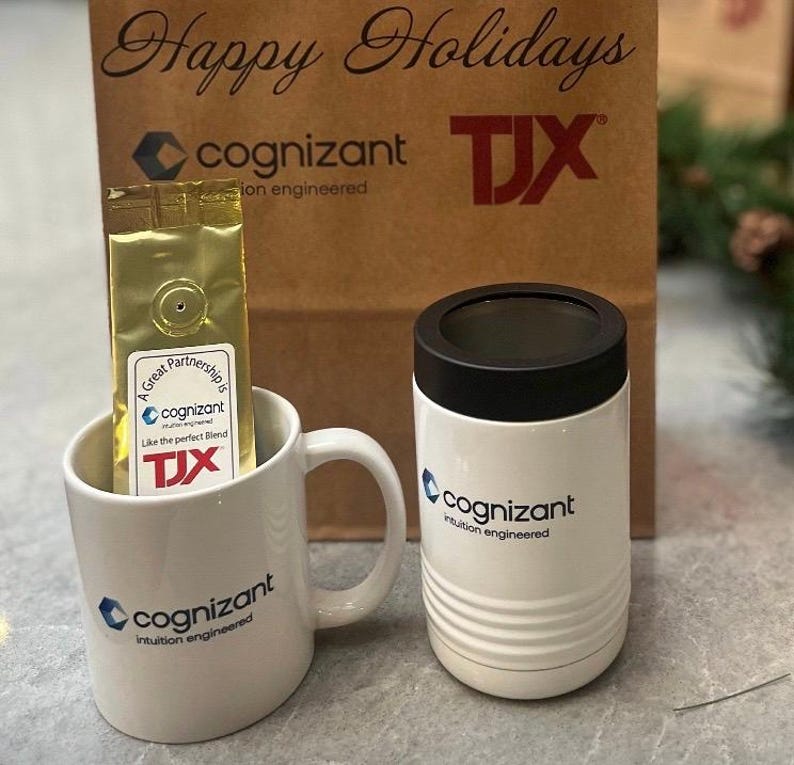 May include: A gift set featuring a white coffee mug and a white tumbler, both branded with the "cognizant" logo. A gold coffee bag is inside the mug. A brown paper bag with "Happy Holidays" and "TJX" printed on it is in the background.