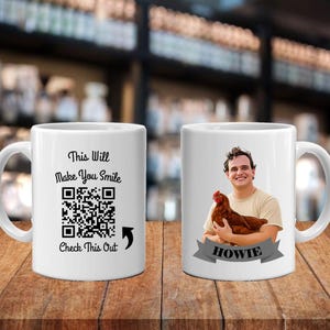 May include: White ceramic mug with the text "This Will Make You Smile" and a QR code. The other side features a person holding a chicken, with the name "HOWIE" on a banner.