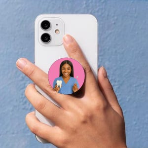 May include: A pink and white phone pop socket with a picture of a woman in a blue scrubs holding a white tooth and a dental tool.