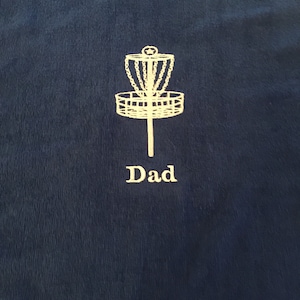 May include: A dark blue towel with a white embroidered disc golf basket and the word "Dad" underneath.