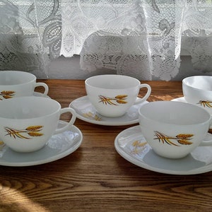 Peut inclure: Ensemble de quatre tasses à thé et soucoupes blanches avec un motif de blé doré.
