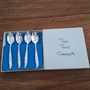Peut inclure: Ensemble de quatre cuillères à café en argent dans une boîte bleue. La boîte porte les inscriptions "Forest Flower" et "Community The Finest Silverplate".
