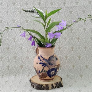 Peut inclure: Un pichet en céramique avec un motif floral bleu et blanc et un motif d'oiseau, rempli de fleurs violettes et de fleurs blanches.