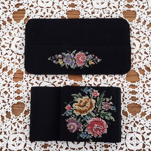 Peut inclure: Deux boîtes recouvertes de tissu noir avec des motifs floraux brodés. La boîte du haut présente une seule rangée de fleurs, tandis que la boîte du bas présente un bouquet de fleurs plus grand.