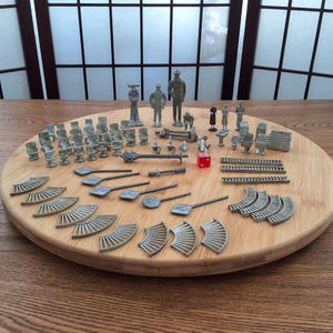 May include: A collection of miniature metal figures and accessories for a model railway set. The set includes people, buildings, fences, and other details. The figures are painted in silver and grey.