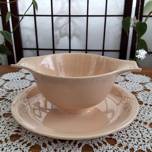 Peut inclure: Un service à sauce et soucoupe de couleur pêche vintage. Le saucier a un bol large et peu profond avec une poignée de chaque côté. La soucoupe est ronde avec un bord légèrement surélevé. L'ensemble est en céramique et a une finition brillante.