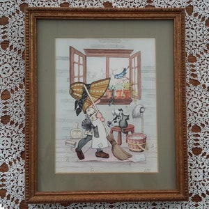 Peut inclure: Une impression encadrée à l'aquarelle représentant une scène fantaisiste d'une personne balayant le sol. La personne porte un grand chapeau et un tablier, avec un chien et un oiseau visibles. Le cadre est de couleur dorée.