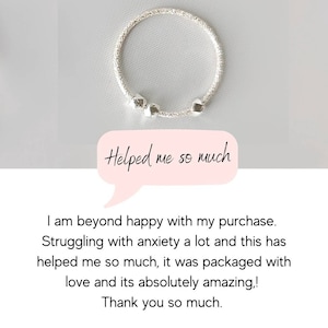 May include: A silver bracelet with three small, cube-shaped charms. The bracelet is on a white background. "Helped me so much" is written in a speech bubble.