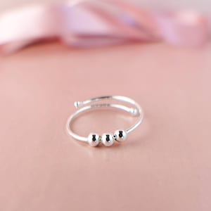 May include: A silver ring with three round beads.