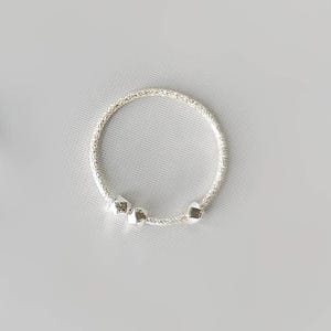 May include: A silver bracelet with a delicate chain and three small, round charms.