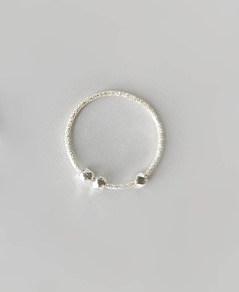 May include: A silver bracelet with a delicate chain and three small, round charms.