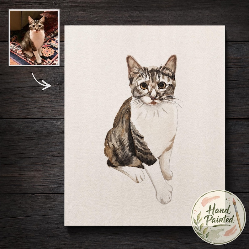 May include: A watercolor painting of a brown and white tabby cat sitting in a forward-facing position. The cat has dark brown stripes on its head and back with a white chest and paws. A small circular sticker in the corner says Hand Painted.