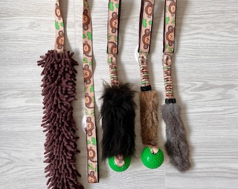 Peut inclure: Cinq jouets pour chien, dont un jouet en peluche marron avec une longue queue hirsute, un jouet en peluche marron et noir avec une longue queue hirsute, une balle verte avec une queue en peluche marron, un jouet en corde marron et vert avec un imprimé singe et un jouet en corde marron et vert avec un imprimé singe.
