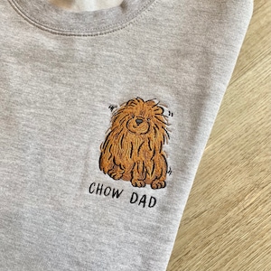 May include: Gray sweatshirt with an embroidered brown Chow Chow dog and the text "Chow Dad" in black.