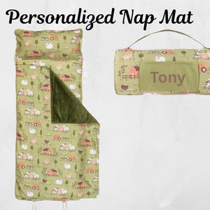May include: A personalized nap mat set with a farm animal pattern. The set includes a rolled-up mat with a handle, and a matching sleeping bag with a pillow. The mat and sleeping bag are light green with a farm animal print, and the sleeping bag has a dark green interior.
