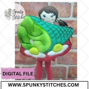 May include: A digital embroidery pattern for a felt doll wearing a green and red mushroom costume. The pattern is available for download from the website "www.spunkyStitches.com".