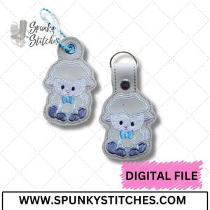 May include: Two embroidered sheep keychains. Each keychain features a light gray sheep with a fluffy head, blue bow tie, and blue feet. One keychain has a blue beaded loop, the other a silver keyring. The text "DIGITAL FILE" is visible.