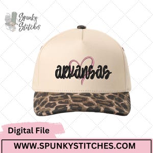 May include: A baseball cap with a cream-colored crown and a leopard print brim. The word "Arkansas" is embroidered in black script with a pink heart. The hat has a black button on top.