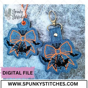 May include: Two blue denim keychains with orange bows and black bats. The bows have a spiderweb design with black bats. The keychains are for sale on the website www.spunkyStitches.com.