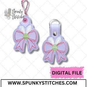May include: Two purple and pink Easter egg bow keychains with a white bunny and green egg design.  The keychains are on a white background with a pink "DIGITAL FILE" banner and the website address "www.spunkyStitches.com".