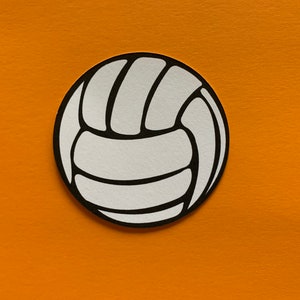 May include: A white volleyball with black outlines, set against an orange background. The ball's design features the classic segmented panels, creating a circular shape. The image is a simple, clean graphic.