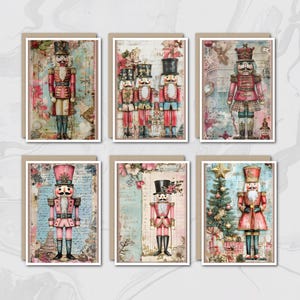 May include: Set of six greeting cards featuring vintage-style illustrations of nutcracker soldiers. Each card showcases a different nutcracker design in shades of red, pink, and blue, with floral and script backgrounds. The cards are rectangular with a white border and a brown cardstock backing.