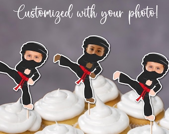 May include: Three black and red ninja cupcake toppers with a space for a photo. The toppers are on cupcakes with white frosting.