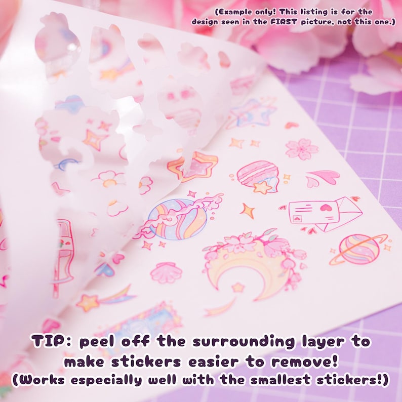 Pode incluir: Uma folha de adesivos rosa pastel e azul com uma variedade de desenhos fofos, incluindo estrelas, luas, planetas, flores e cora&ccedil;&otilde;es. Os adesivos est&atilde;o em um fundo branco e est&atilde;o parcialmente descolados para mostrar os desenhos. O texto "TIP: peel off the surrounding layer to make stickers easier to remove! (Works especially well with the smallest stickers!)" est&aacute; impresso na parte inferior da folha.